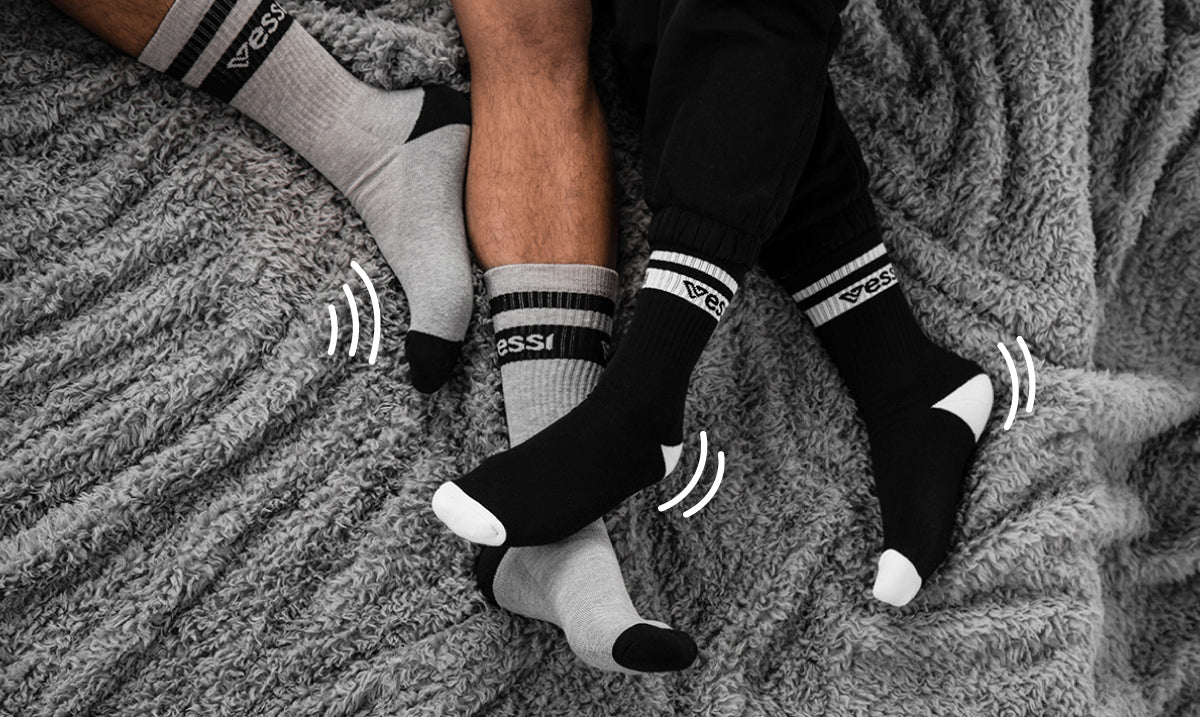 Two people wearing Vessi crew socks on their bed.