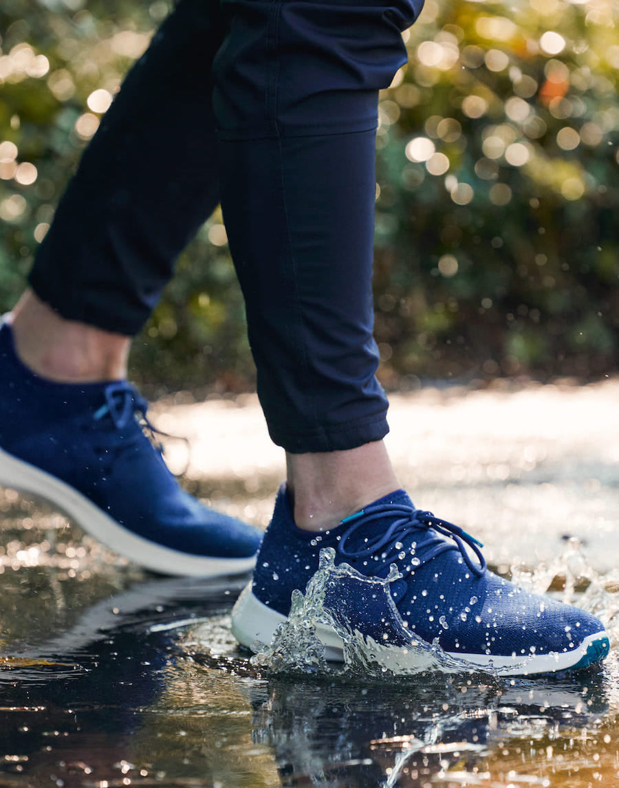 man walking through a puddle with waterproof sneakers